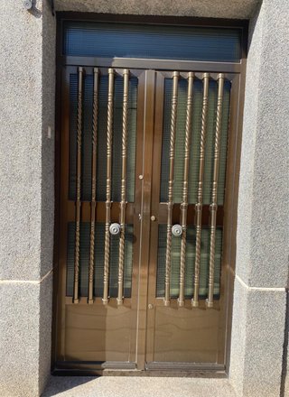 Puerta doble entrada aluminio color bronce.