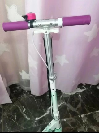 Patinete blanco con ruedas rosas.