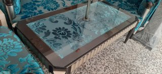 Sofá de tela azul con mesa de cristal y lampara pi