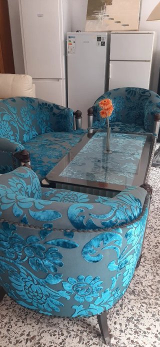 Sofá de tela azul con mesa de cristal y lampara pi