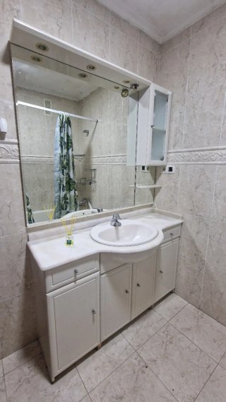 Mueble de baño con espejo, armario y grifo.