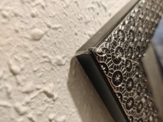 Espejo de cerámica negro y plateado con apoyo.