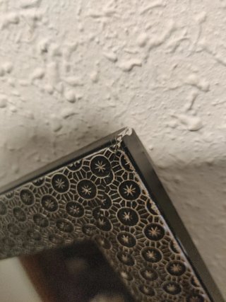 Espejo de cerámica negro y plateado con apoyo.