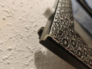 Espejo de cerámica negro y plateado con apoyo.