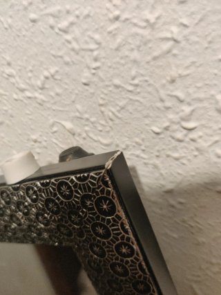 Espejo de cerámica negro y plateado con apoyo.