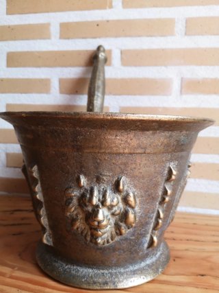 Mortero de bronce antiguo con escudo y figura