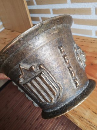 Mortero de bronce antiguo con escudo y figura
