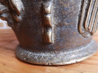 Mortero de bronce antiguo con escudo y figura