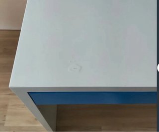 Mesa blanca con cajón azul y silla con ruedas