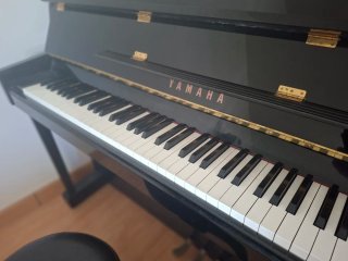 Piano Yamaha negro con banqueta y metrónomo.