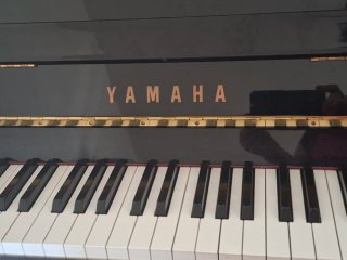 Piano Yamaha negro con banqueta y metrónomo.