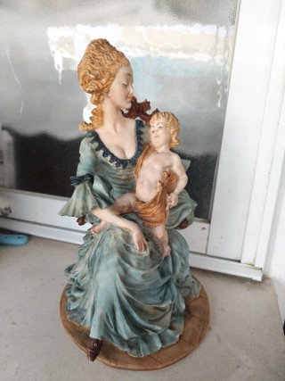 Figura mujer con niño en su regazo sentados .