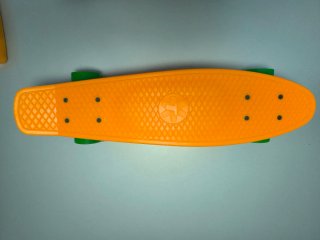 Monopatín naranja con ruedas verdes