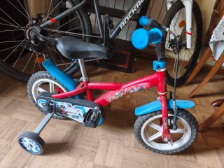 Triciclo infantil rojo con ruedas de apoyo