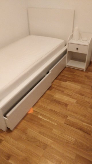 Cama blanca con colchón y mesita