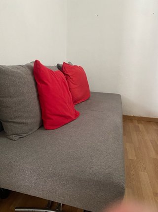 Sofá-cama IKEA ASARUM gris con cojines rojos