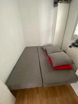 Sofá-cama IKEA ASARUM gris con cojines rojos