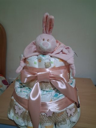 Tarta de pañales con peluche de conejo.