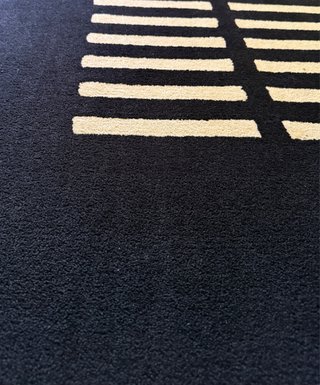 Alfombra negra con diseño geométrico beige
