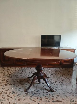 Mesa de salón de madera maciza oscura extensible.