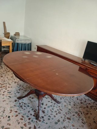 Mesa de salón de madera maciza oscura extensible.