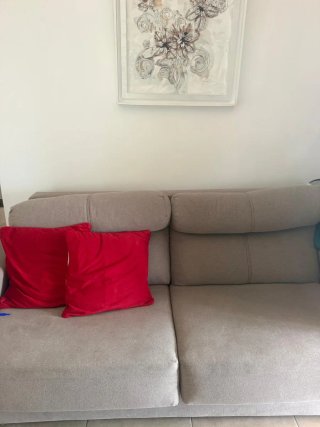 Sofá de tela beige con cojines rojos