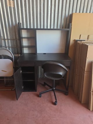 Escritorio negro con silla y estanterías