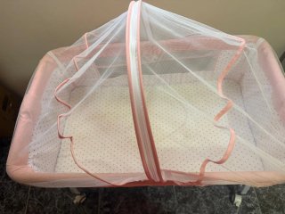 Cuna de bebé rosa con mosquitera