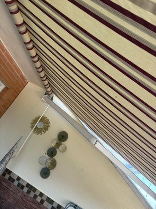 Toldo de tela beige y rojo con volante .