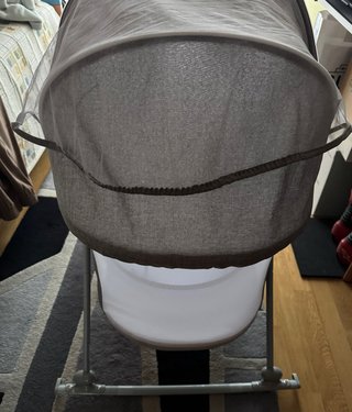 Cuna de bebé gris con capota y juguetes