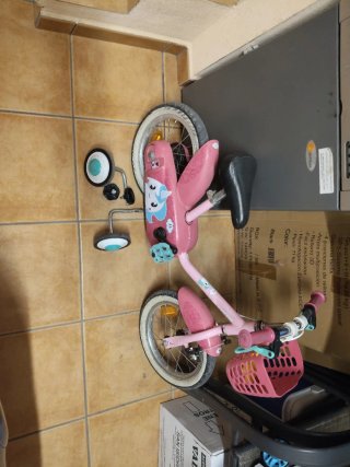 Bicicleta infantil rosa con cesta y ruedines.