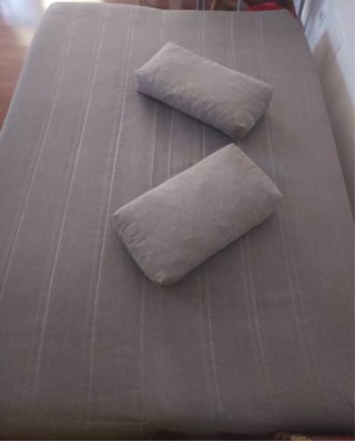 Sofá cama gris con canapé, dos cojines.