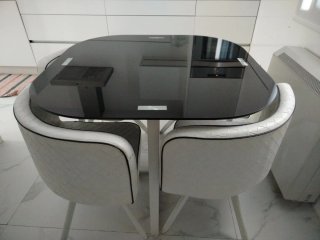 Mesa cuadrada de cristal y 4 sillas blancas.
