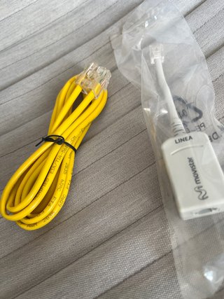 Cable de red amarillo y adaptador Movistar
