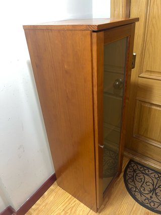 Estantería de madera con puerta de cristal.