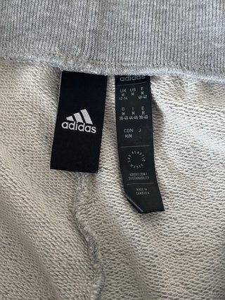 Chándal Adidas gris con flores naranjas.