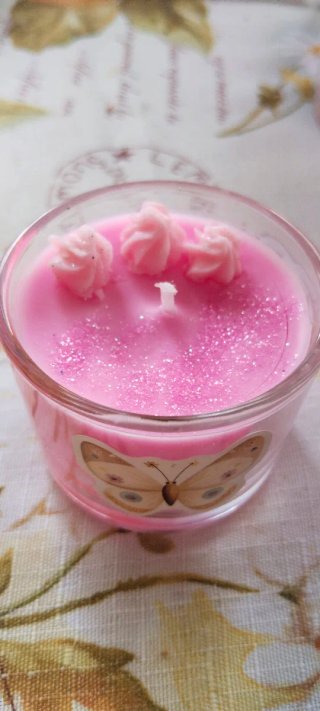 Vela rosa con flor y mariposa