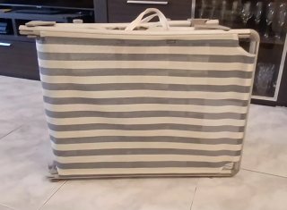 Tumbona plegable gris con bamdas blanco y azul.