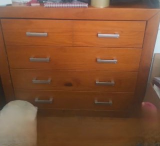 Cómoda de madera con 5 cajones y asas de plástico.