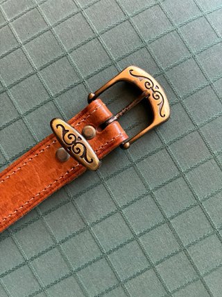 Cinturón de cuero con detalle dorado.