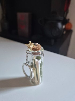 Llavero con botella de huesos y musgo