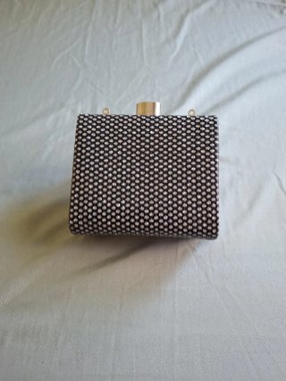 Cartera de fiesta negra con detalles plateados.