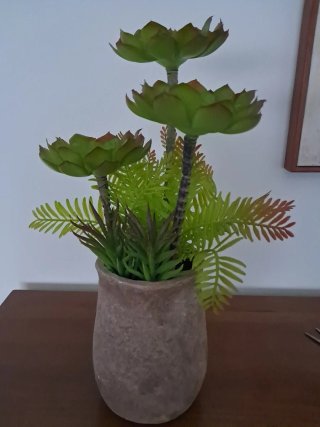Maceta terracota con plantas artificiales.