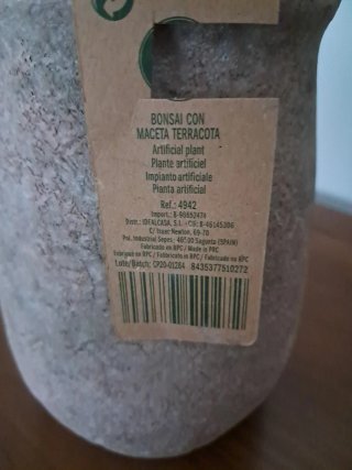 Maceta terracota con plantas artificiales.