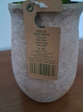 Maceta terracota con plantas artificiales.