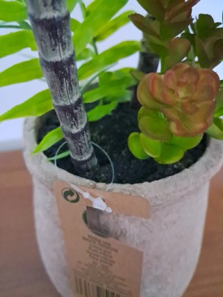 Maceta terracota con plantas artificiales.