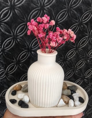 Jarrón blanco con flores secas y piedras