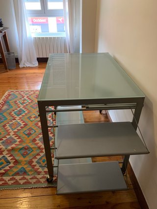 Escritorio de cristal y metal gris con ruedas