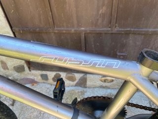 Bicicleta BMX plateada con detalles naranjas,