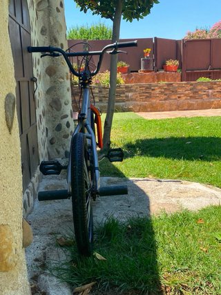Bicicleta BMX plateada con detalles naranjas,